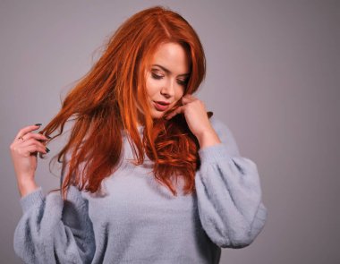 Genç ve çekici kızıl saçlı kız kameraya bakıp gülümsüyor.