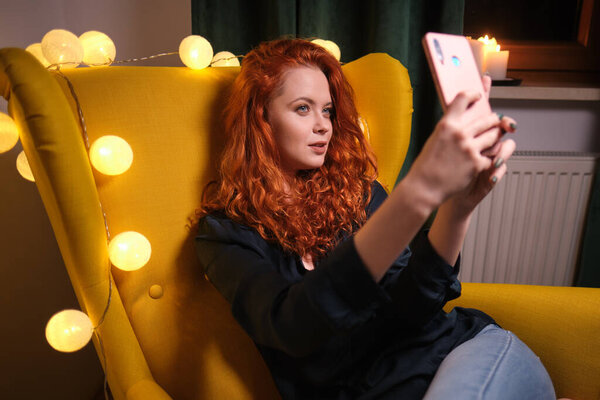 Красивая девушка использует свой смартфон на диване дома в гостиной