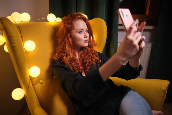 Красивая девушка использует свой смартфон на диване дома в гостиной