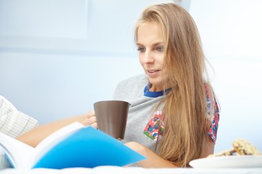 Yatakta kitap okuyan kadın