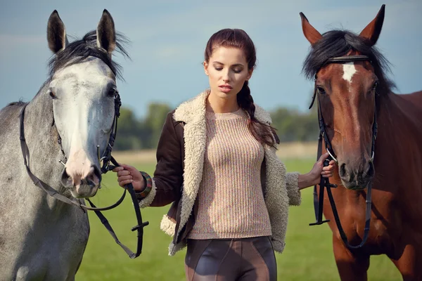 Mulher e dois cavalos ao ar livre — Fotografia de Stock