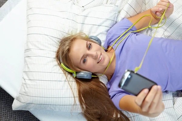 Жінка лежить на ліжку, слухаючи музику — стокове фото
