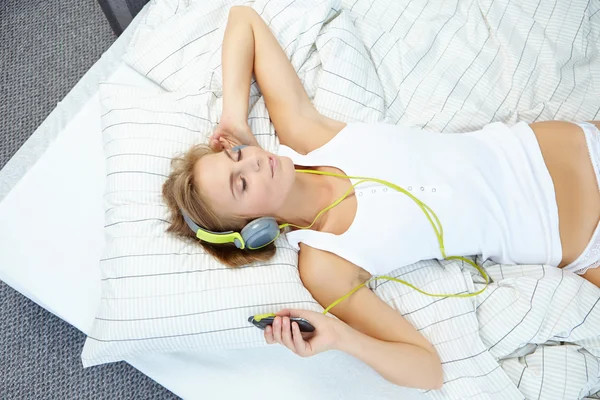 Frau liegt beim Musikhören im Bett — Stockfoto