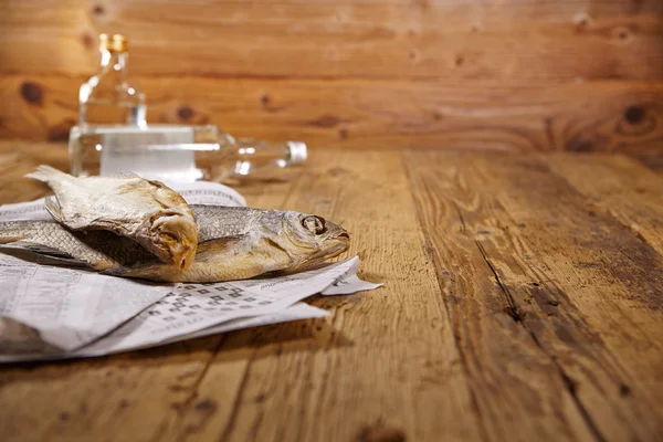 Vodka and dried fish on wooden table — Stock Photo, Image