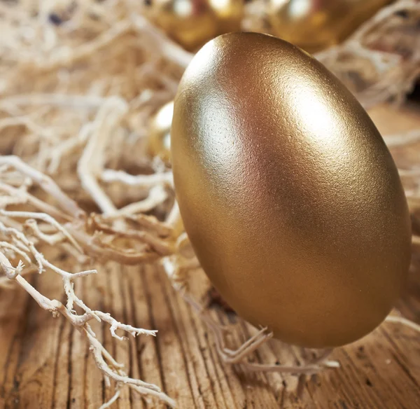 Golden eggs in nest on dark — Stock Photo, Image