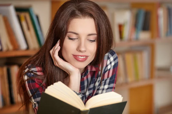 Student håller en bok i biblioteket — Stockfoto