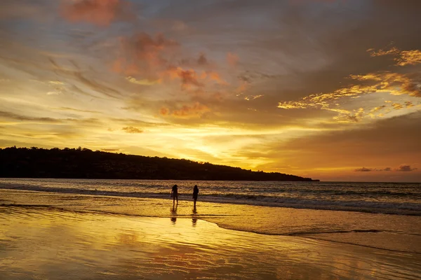 Силуети пар на пляжі під час заходу сонця — стокове фото