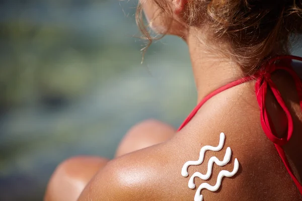 Femme avec crème solaire à la plage — Photo