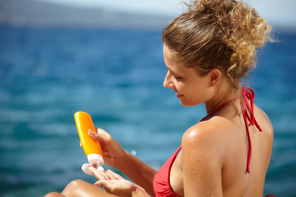 Frau cremt sich mit Sonnenschutz ein — Stockfoto