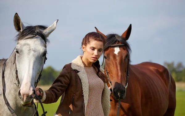 Mooie vrouw en twee paarden buiten — Stockfoto