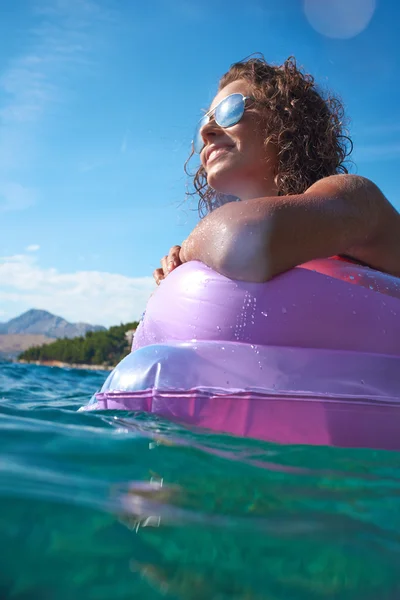 Девушка, плавающая на матрасе — стоковое фото
