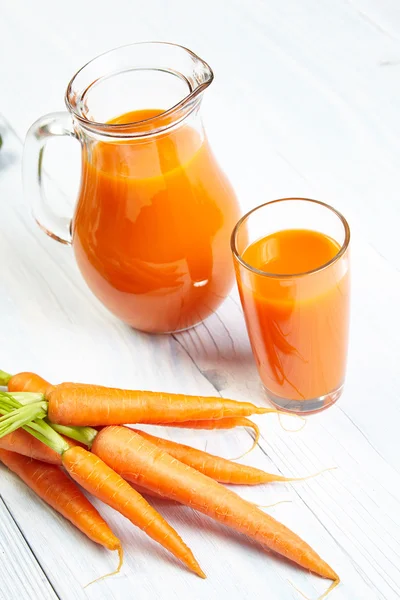 Морковный сок на столе из белого дерева — стоковое фото