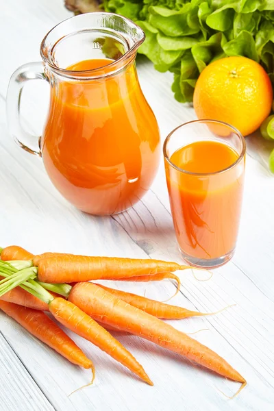 Морковный сок на деревянном столе — стоковое фото