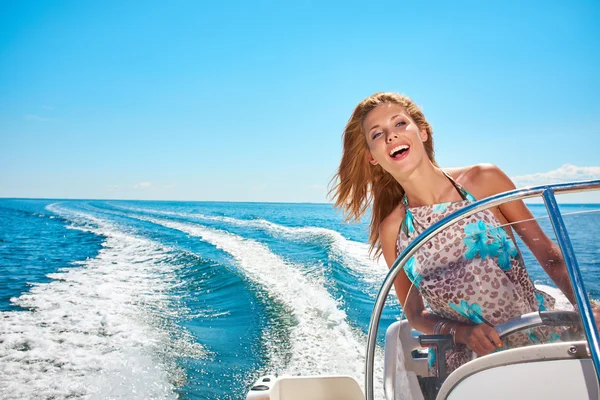 Mujer joven conduciendo un barco a motor — Foto de Stock