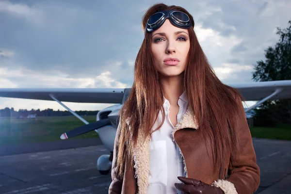 Beautiful woman pilot in front of airplane — Stock Photo, Image