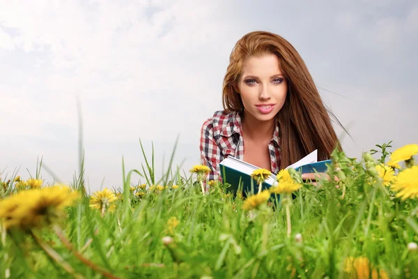 Woman on green field and reads book — Stock Photo, Image