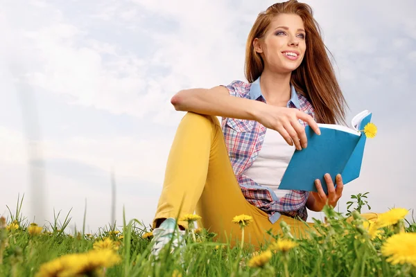 Femme sur le champ vert et livre de lecture — Photo