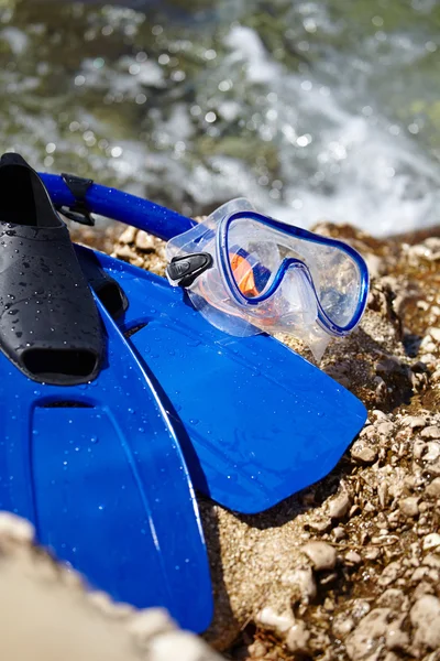 Mascarilla y aletas en una playa de rocas — Foto de Stock