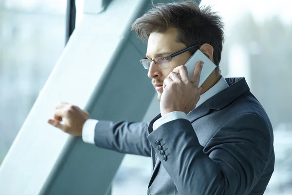 Businessman talking on mobile phone in office lobby — Stock Photo, Image