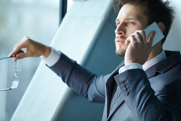 Businessman talking on mobile phone in office lobby — Stock Photo, Image