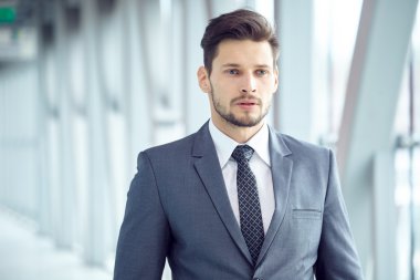 Takım elbiseli bir işadamı ofiste duruyor.