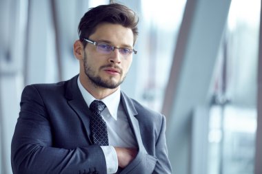 Takım elbiseli bir işadamı ofiste duruyor.