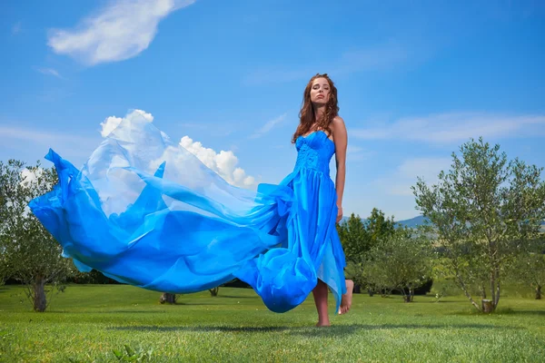 Женщина в синем платье позирует с небом на заднем плане — стоковое фото