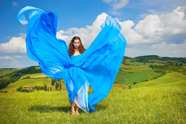 Woman in blue dress in green hills — Stock Photo, Image