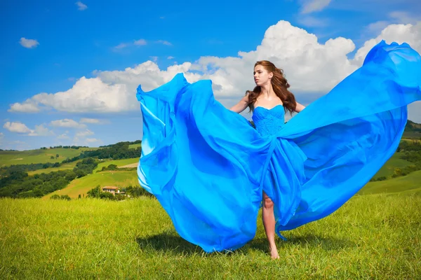 Vrouw in blauwe jurk in groene heuvels — Stockfoto