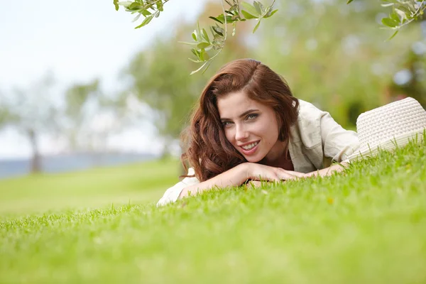 Usměvavá mladá dívka leží na trávě — Stock fotografie