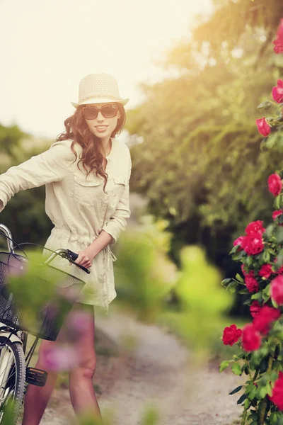 Mujer con bicicleta en jardín de rosas — Foto de Stock