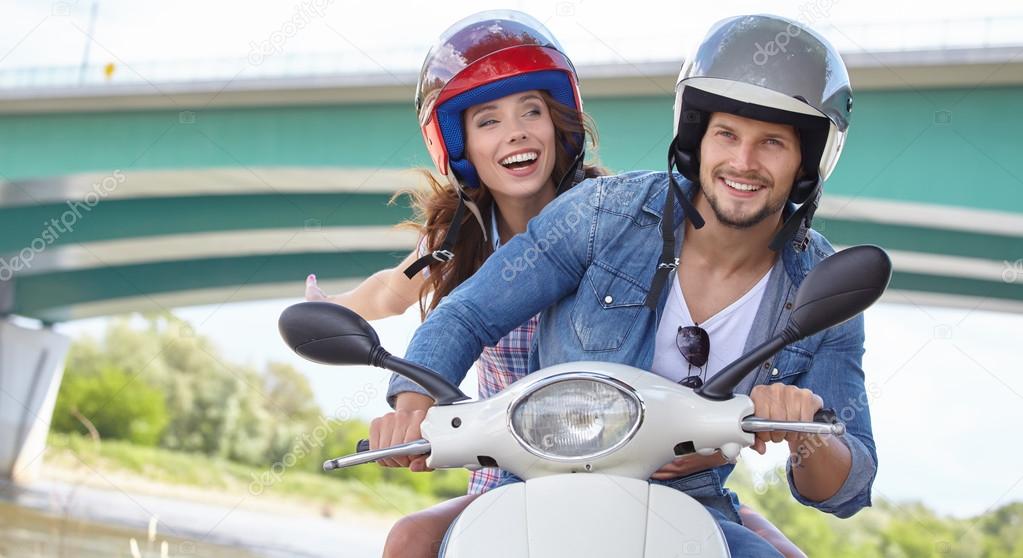 couple riding vintage scooter