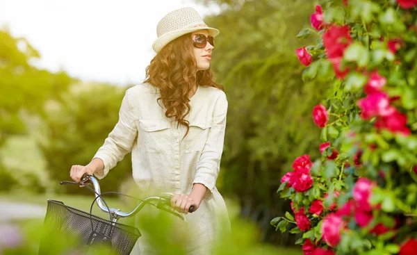 Mulher com bicicleta no jardim de campo — Fotografia de Stock