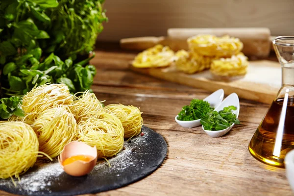 Pasta ingredients on table, with little olive oil bottle and rol — Stock Photo, Image