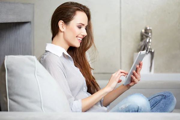 Женщина с цифровым планшетом на диване — стоковое фото