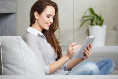 Kanepede dinlenirken dizüstü bilgisayar kullanan bir kadın.