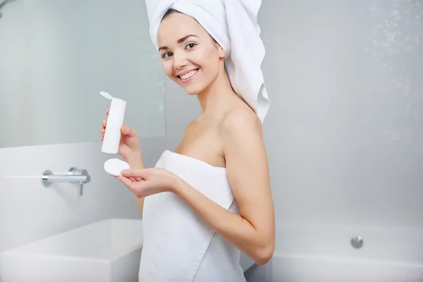 Mujer envuelta con toallas de baño, aplicación de crema en su cara — Foto de Stock