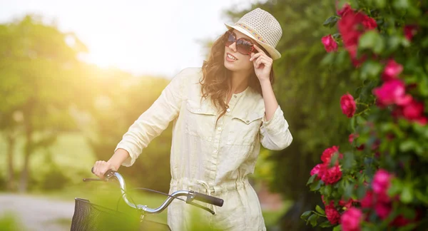 Женщина с велосипедом в саду — стоковое фото