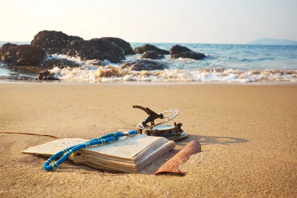 Пляж с винтажными солнечными часами и ноутбуком — стоковое фото