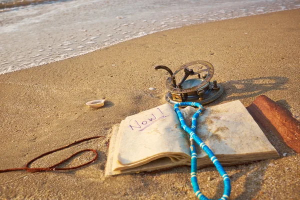Пляж с винтажными солнечными часами и ноутбуком — стоковое фото