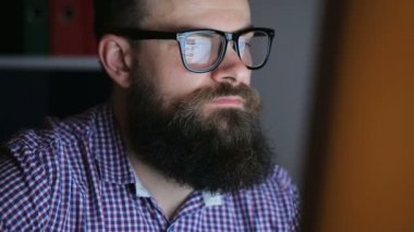Bilgisayarda çalışan yorgun genç sakallı adam