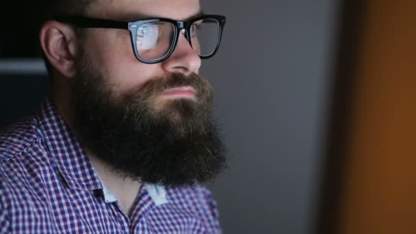 Fáradt fiatal szakállas férfi, a számítógépen dolgozik — Stock videók