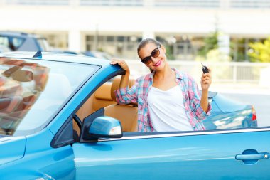 Üstü açık araba ile yakın duran güneş gözlüklü genç güzel kadın 