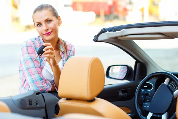 Junge Frau steht neben einem Cabrio mit Schlüssel in der Hand — Stockfoto