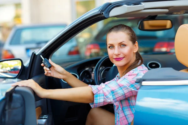 Jovem mulher bonita sentada em um carro conversível com as chaves em — Fotografia de Stock