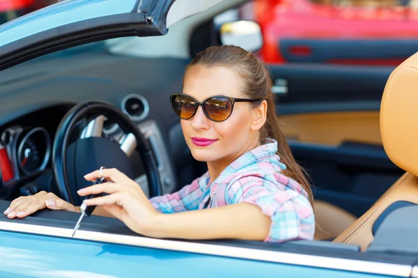 Mujer bonita joven en gafas de sol sentado en un coche convertible wi — Foto de Stock