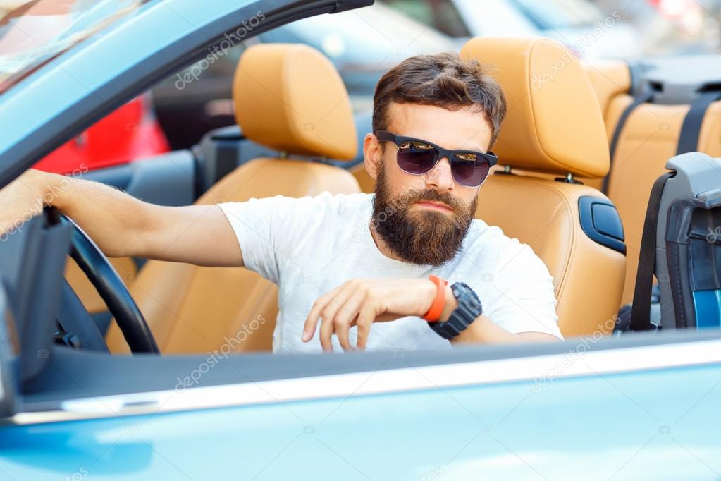 Young bearded man sitting in a convertible