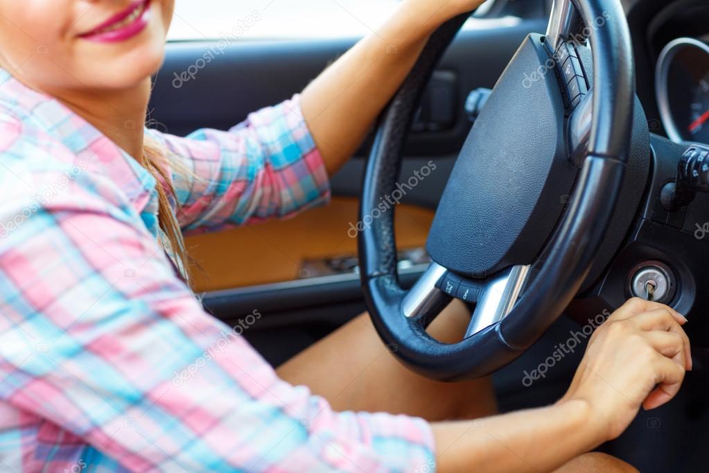 Woman sitting in a convertible and is going to start the engine