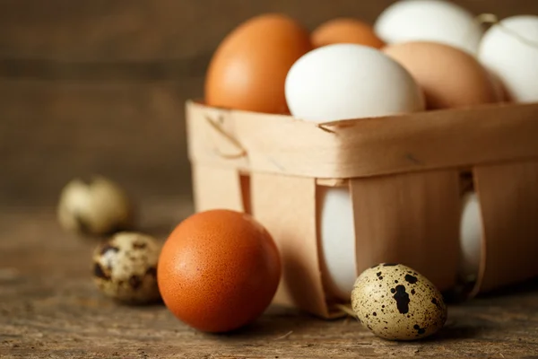 Huevos de pollo y codorniz sobre un fondo rústico de madera — Foto de Stock