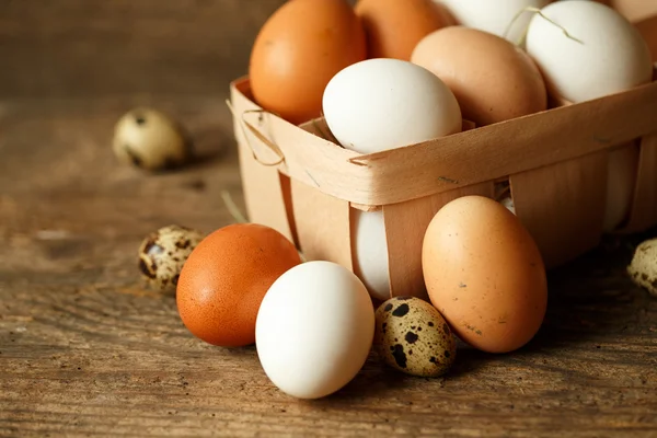 Uova di pollo e quaglia su uno sfondo rustico in legno — Foto Stock